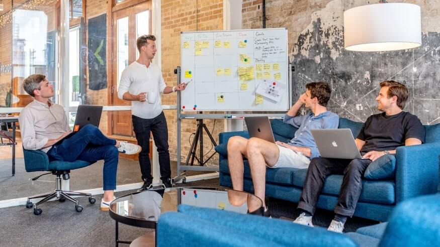 Couple of team members in an office, discussing idea presented on a white board