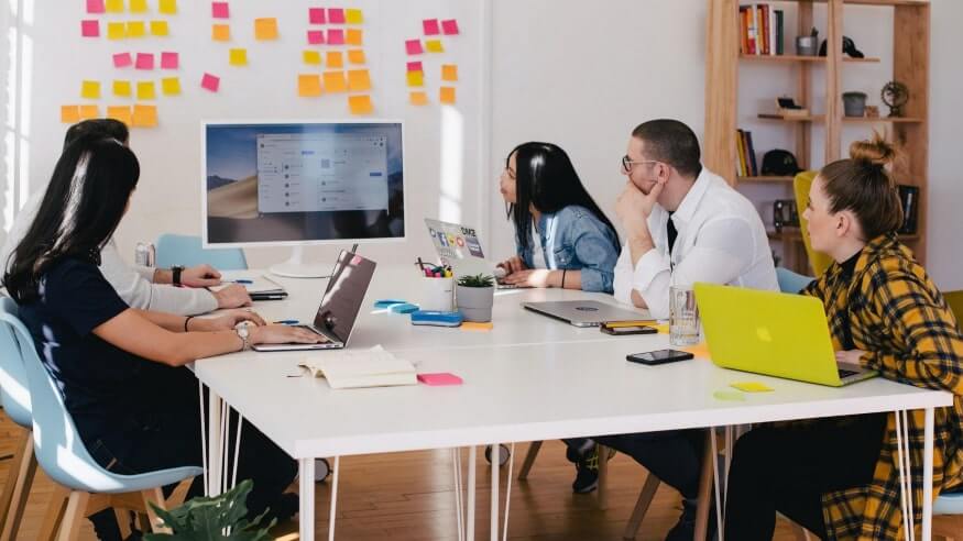 Bunch of professionals in the office looking at stick notes on the office wall