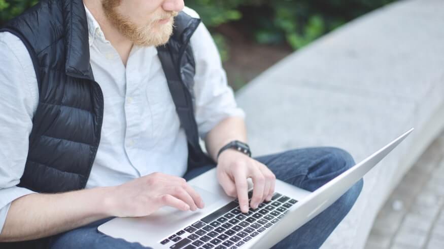 Man sitting outdoors and working on his laptop